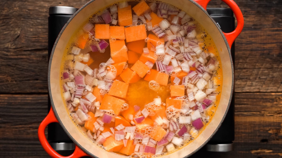 Sweet Potatoes and onions added to the water and broth in the Dutch oven