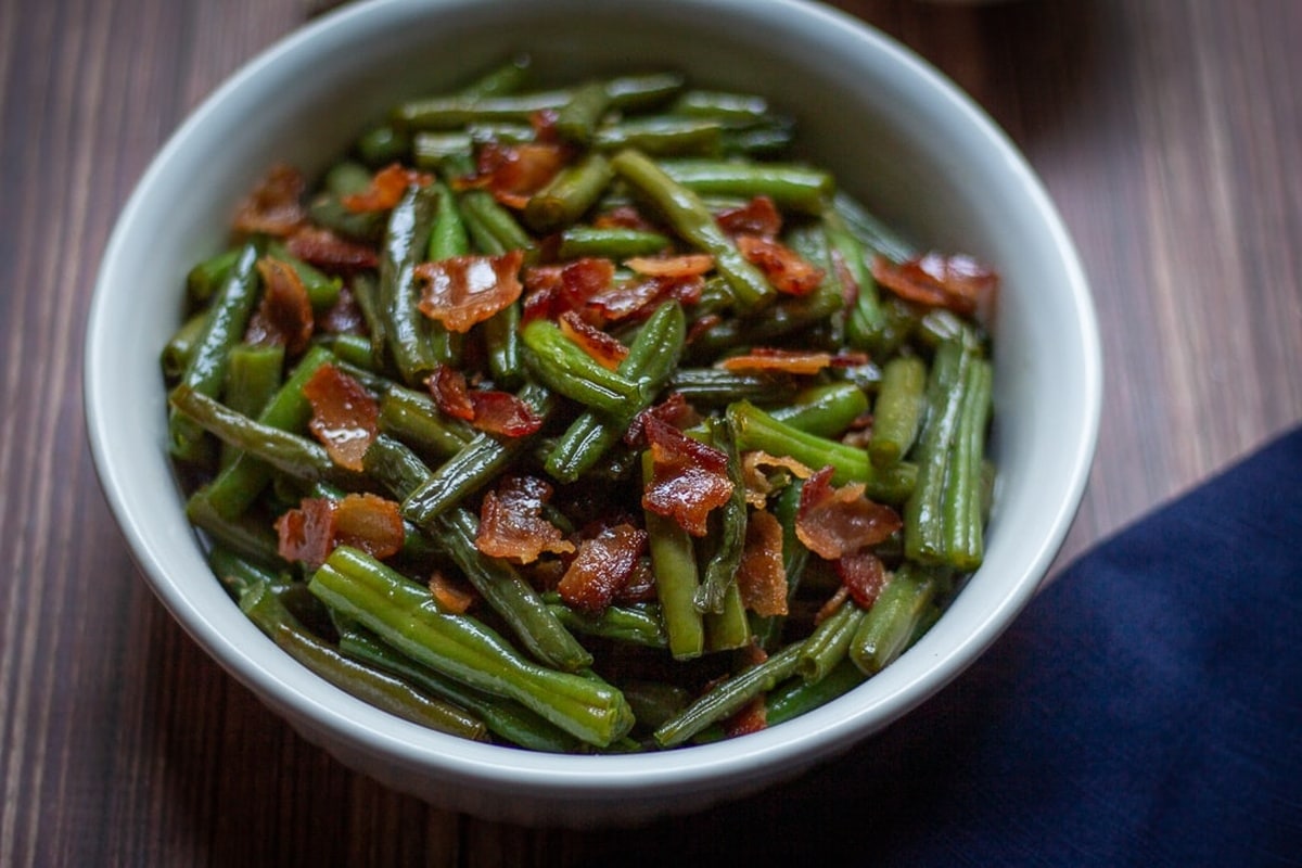 Arkansas green beans in a bowl, garnished with crispy bacon.