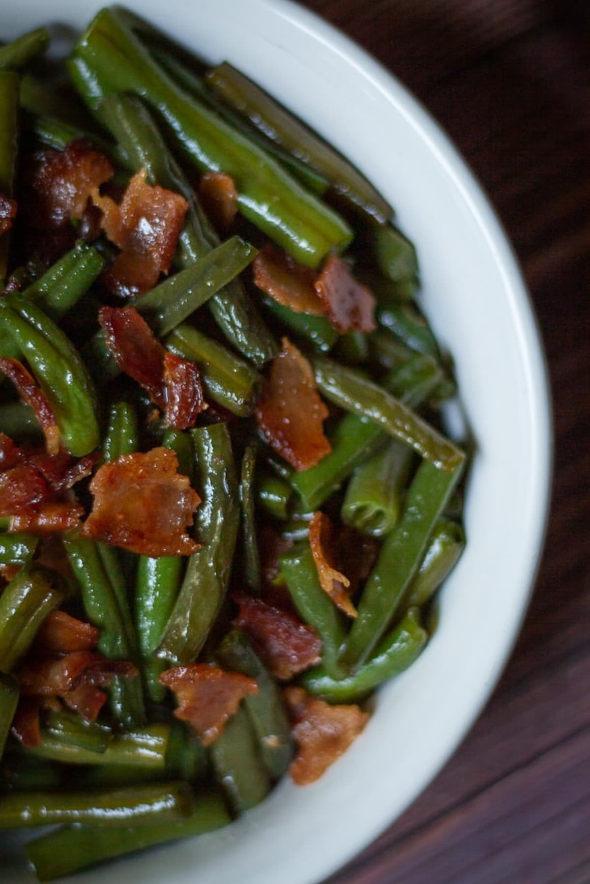 Green beans served in a bowl, garnished with bacon.