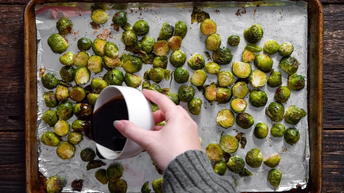 Balsamic vinegar and honey glaze poured onto cooked Brussels sprouts.