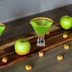 Two glasses of caramel apple martini on a table.
