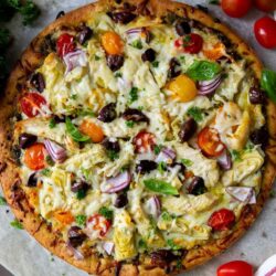 This Chicken Pesto Pizza recipe is quick and easy to make, with a delicious flavor from the basil pesto sauce, chicken, artichoke hearts, cherry tomatoes, red onion, Kalamata olives and lots of mozzarella cheese!