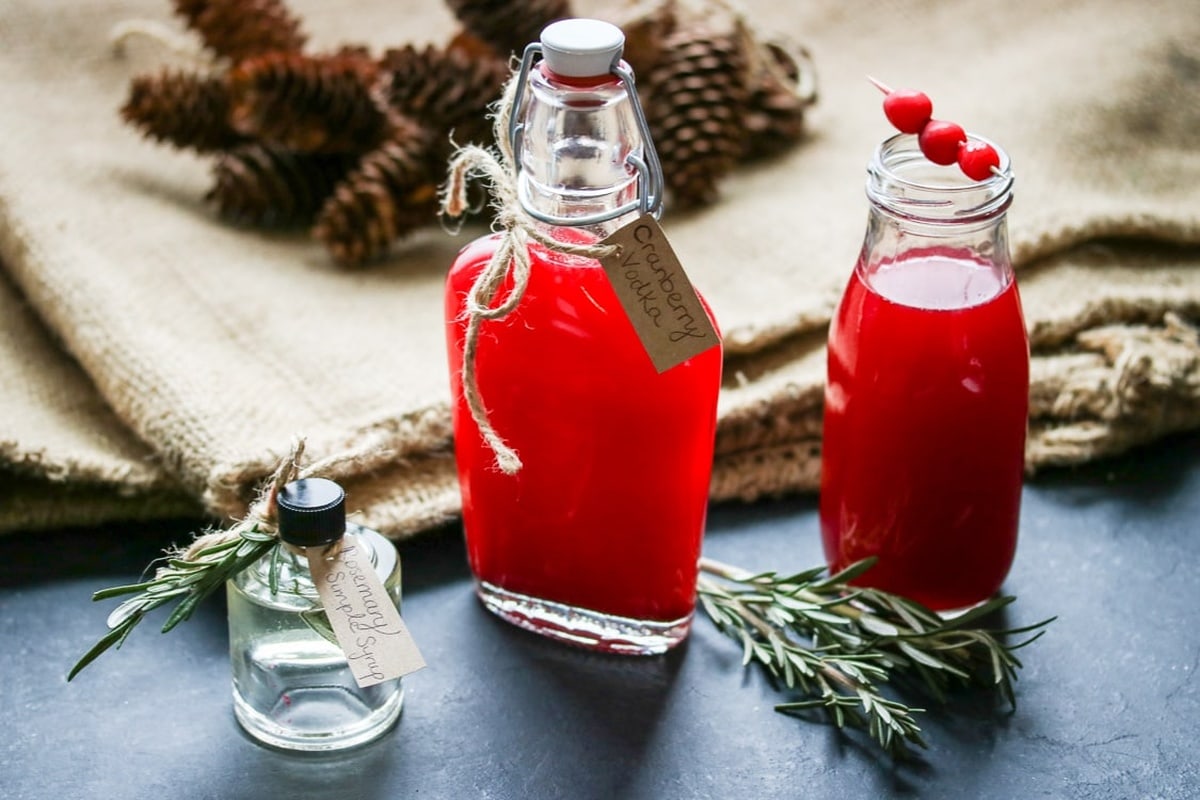 Jars of cranberry vodka and a jar of rosemary simple syrup.