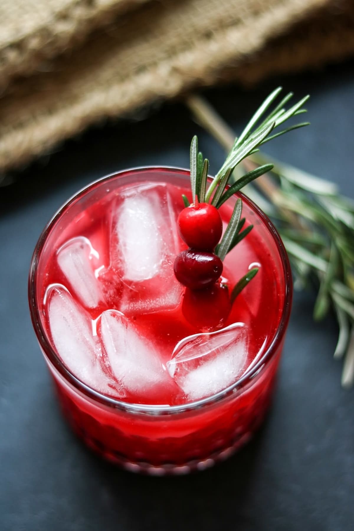 Cranberry vodka spritzer over ice with rosemary sprig.