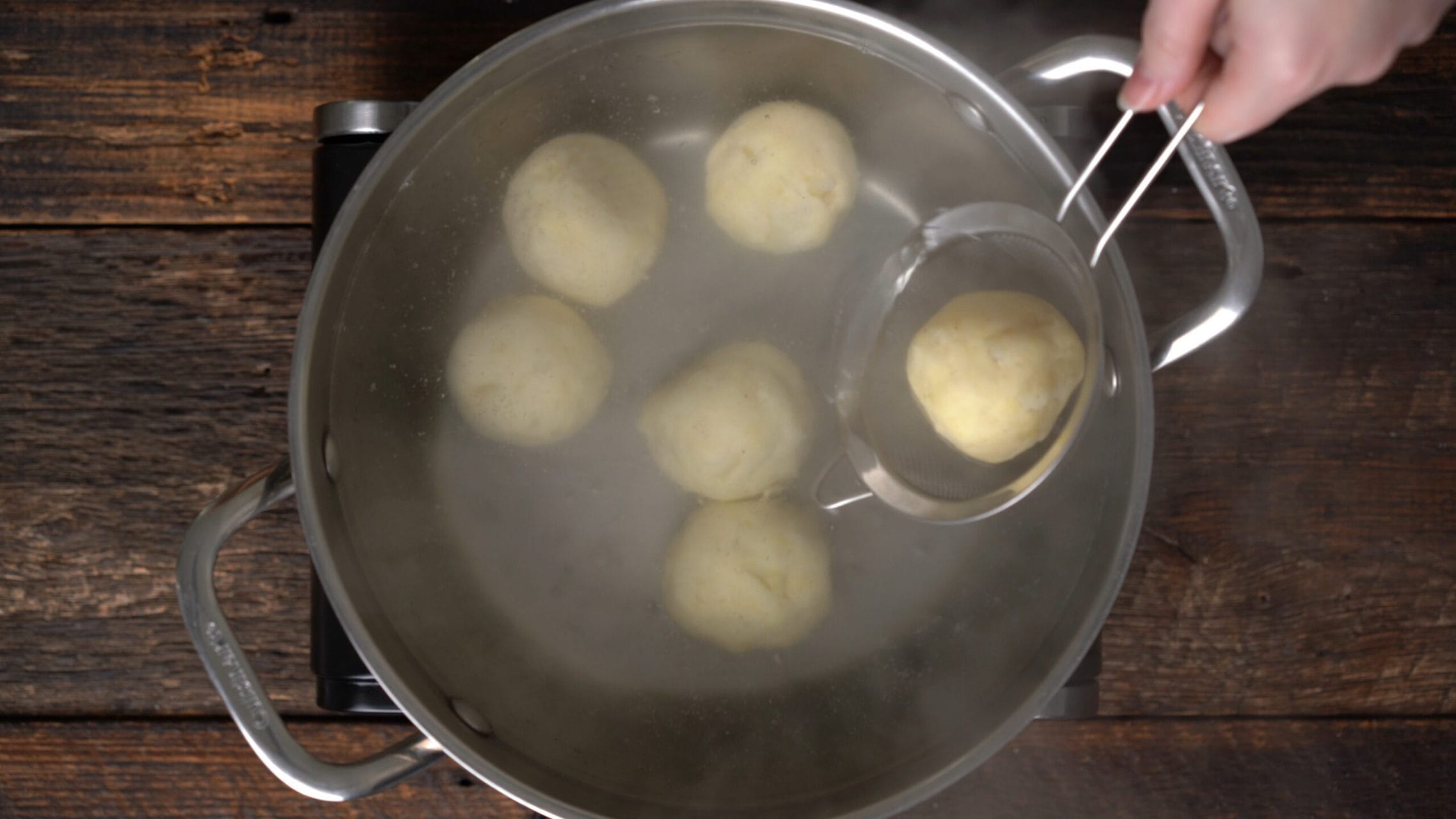 german potato dumplings cooking in water in a pan