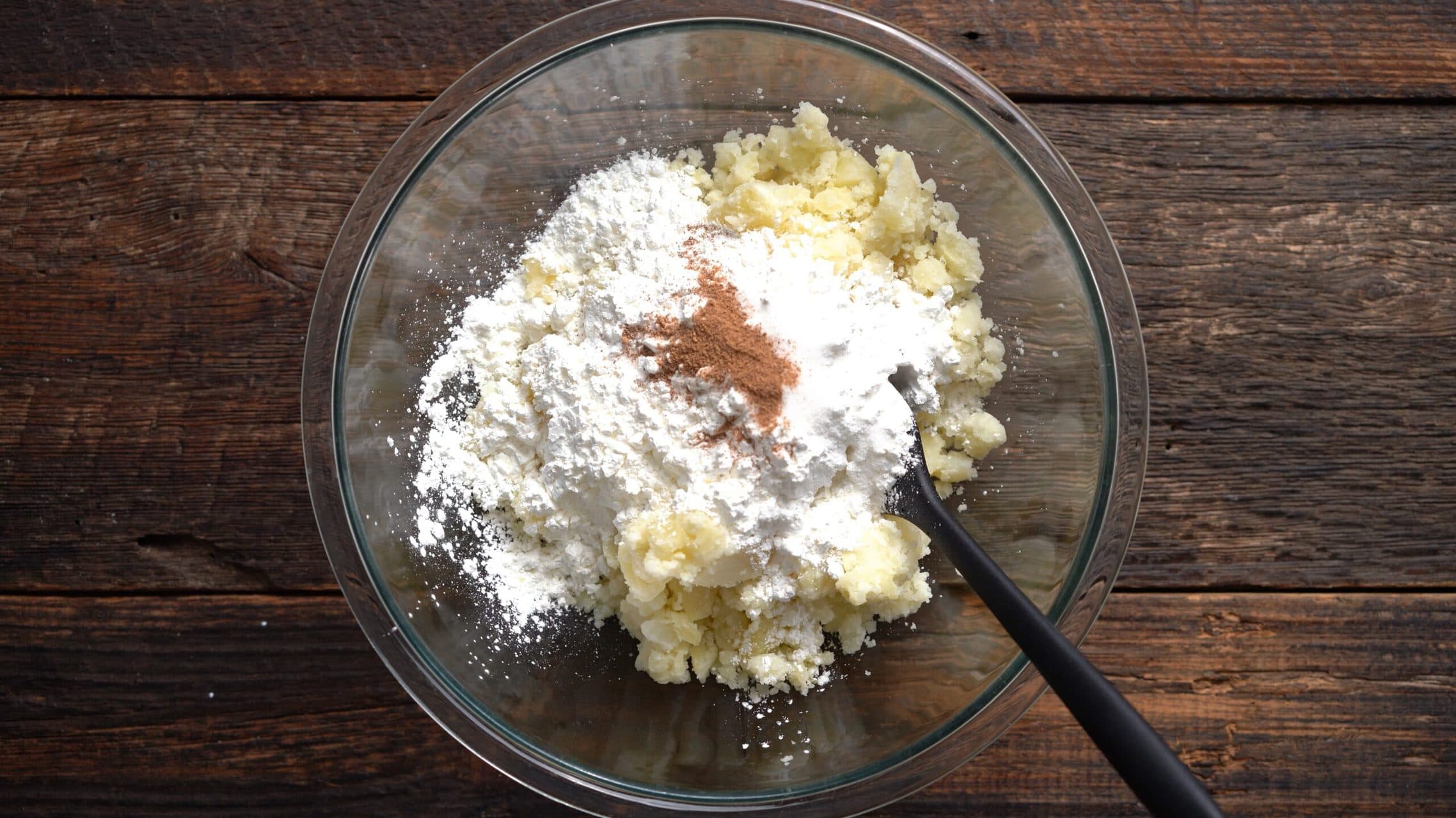 mashed potatoes in a bowl with corn starch, salt and nutmeg added on top