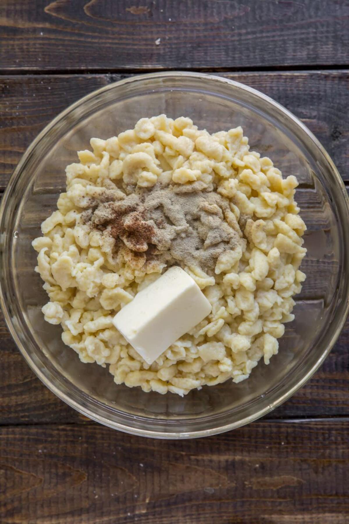 German Spaetzle in a clear bowl with butter and spices added.