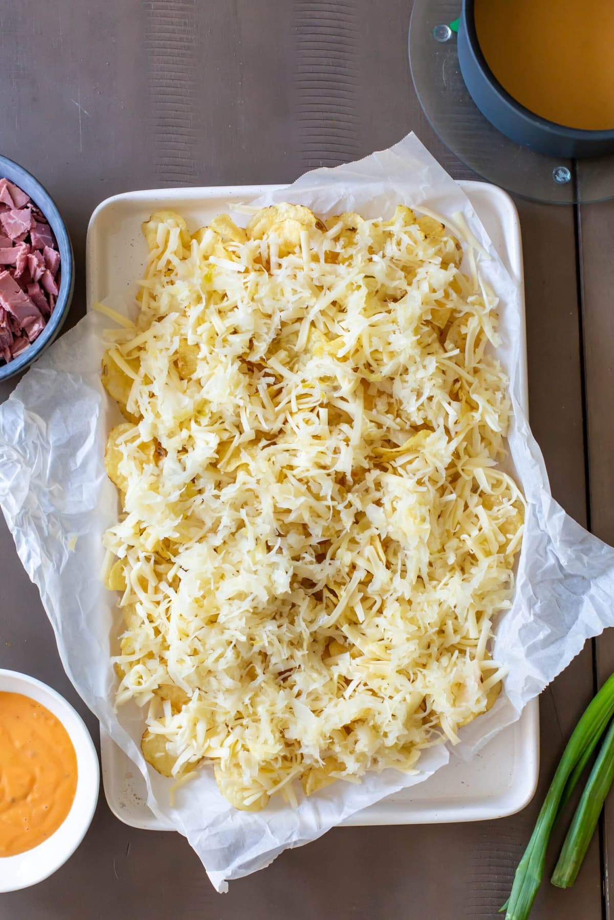 A plate of potato chips is topped with sauerkraut on top of the Swiss cheese.