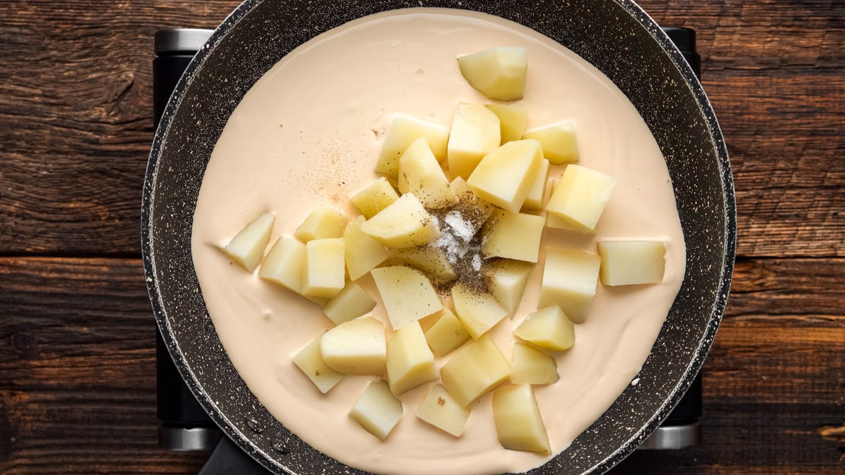 Potatoes and light cream cooking in a skillet.