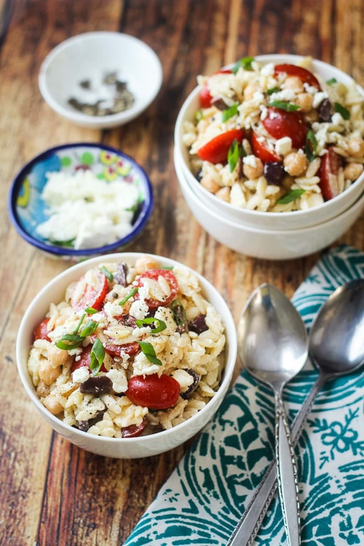 Two servings of Mediterranean Orzo Pasta Salad in bowls, placed on a table.