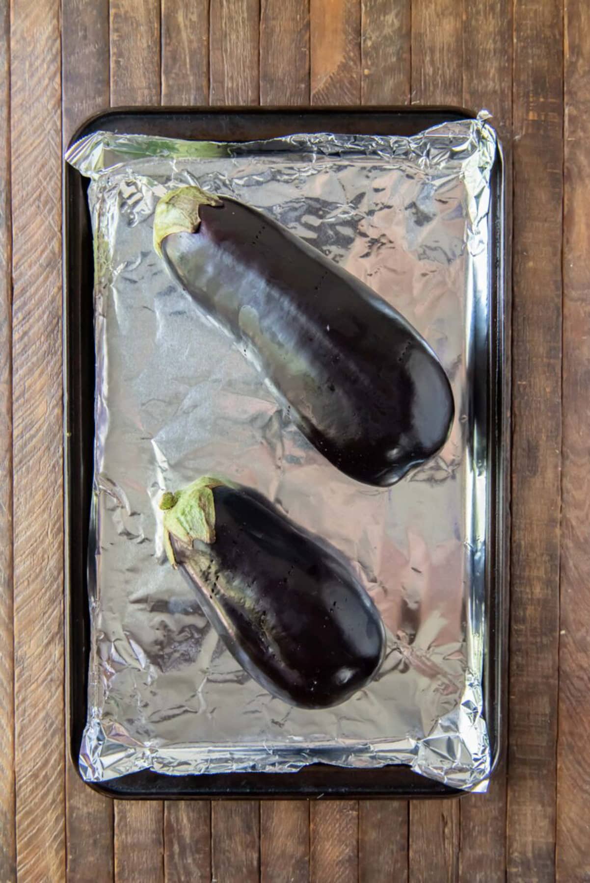 Eggplants prepped on a baking sheet before baking.