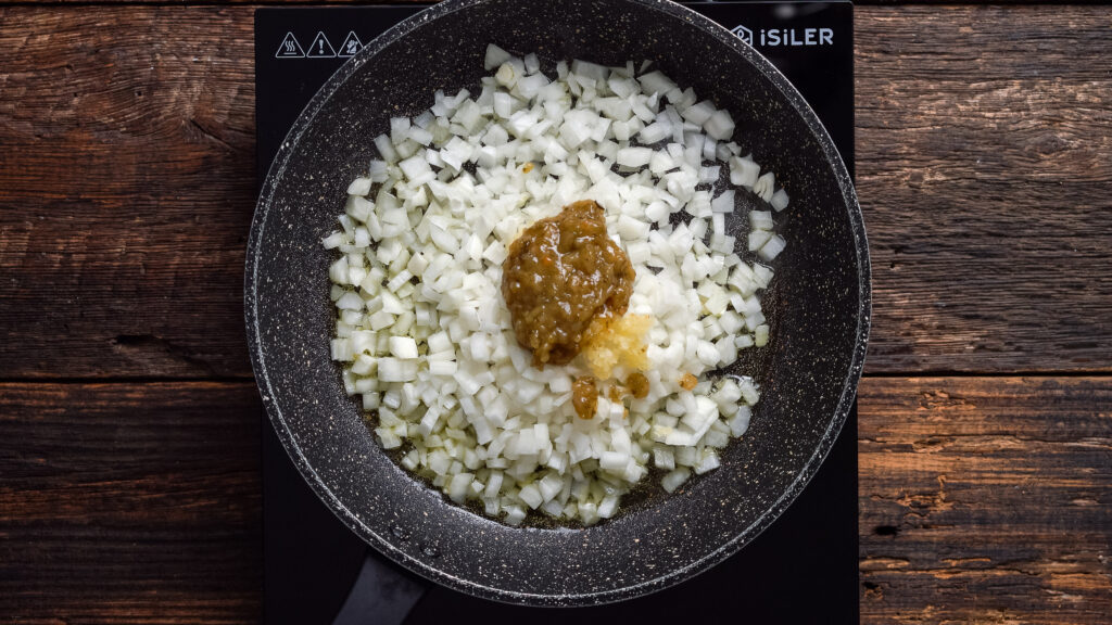 Onions, sofrito, and garlic cooking in a skillet for empanadas puerto rican