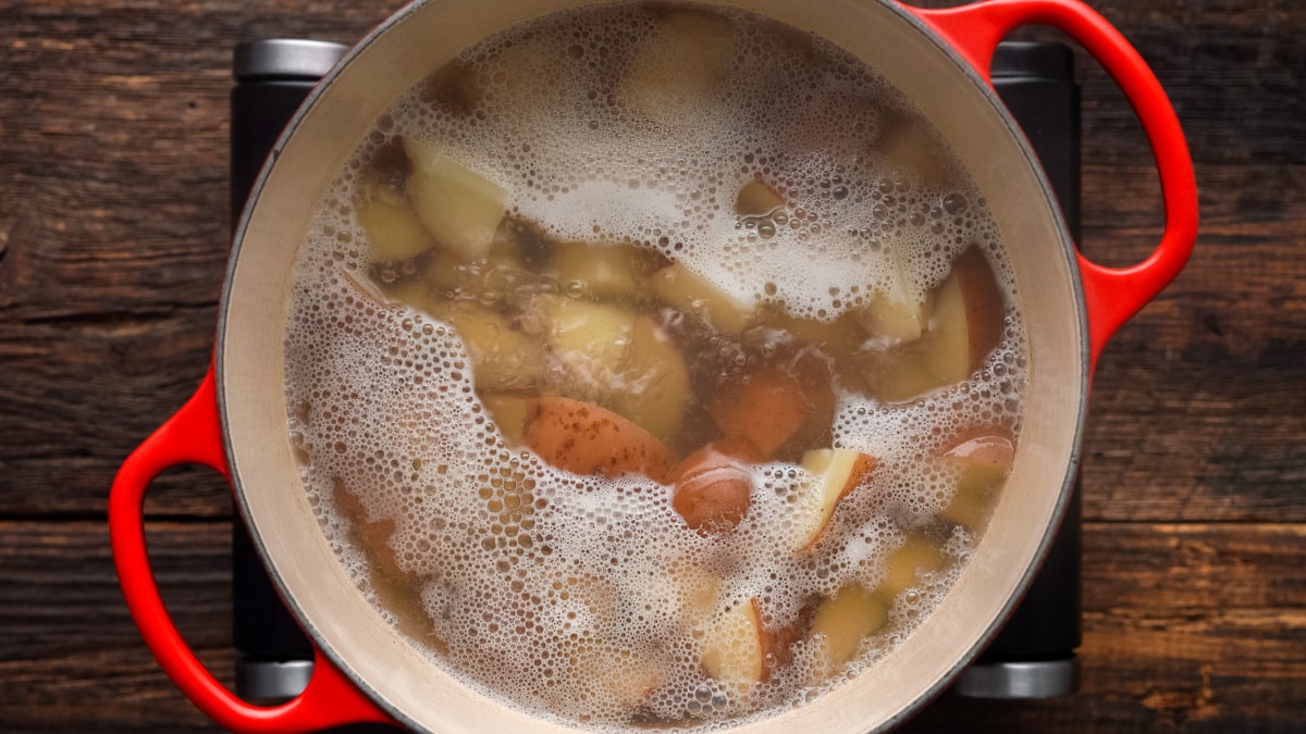 Red potatoes boiling in a pot.