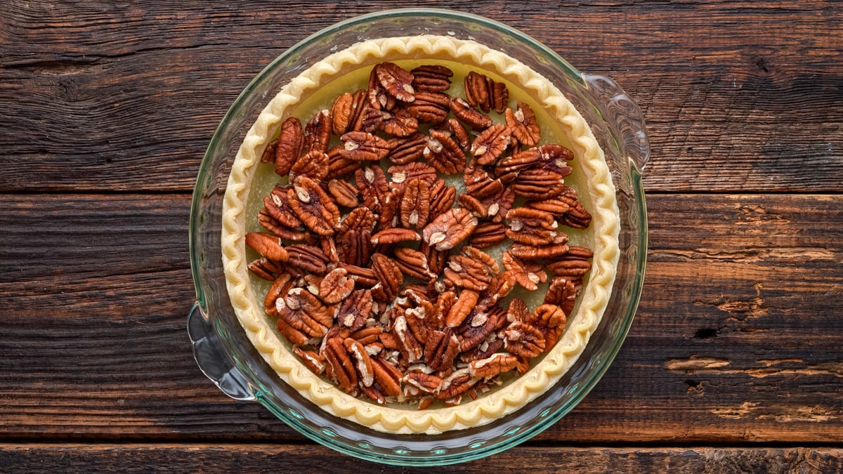 Pecan halves being added to the pie crust.