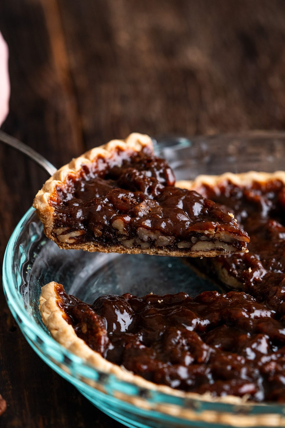 Slice of vegan pecan pie being lifted out of the pie plate with a pie server.