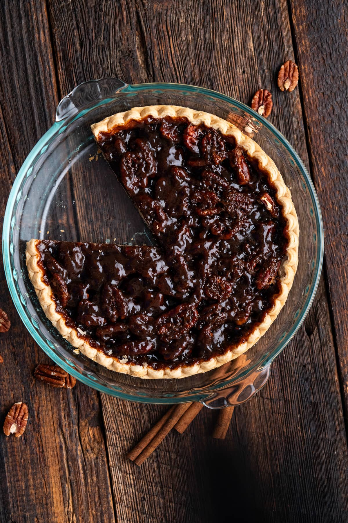 Vegan pecan pie in a glass pie plate with a slice missing.